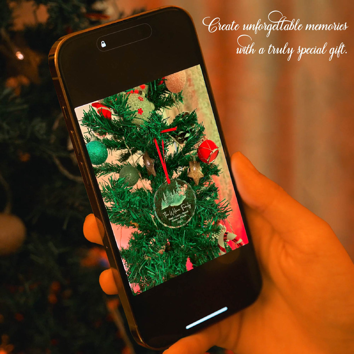 Personalized glass ornament hanging on a Christmas tree with a red ribbon