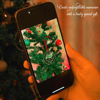 Personalized glass ornament hanging on a Christmas tree with a red ribbon